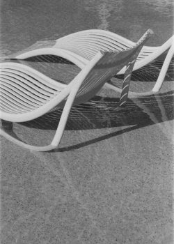 An abstract close up of two white lounge chairs sitting in the shallow end of a pool