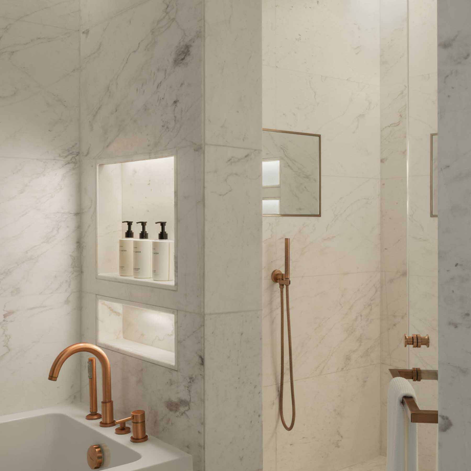 a white marble bathroom with a separate rainfall shower and bathtub with luxurious bath amenities available to guests
