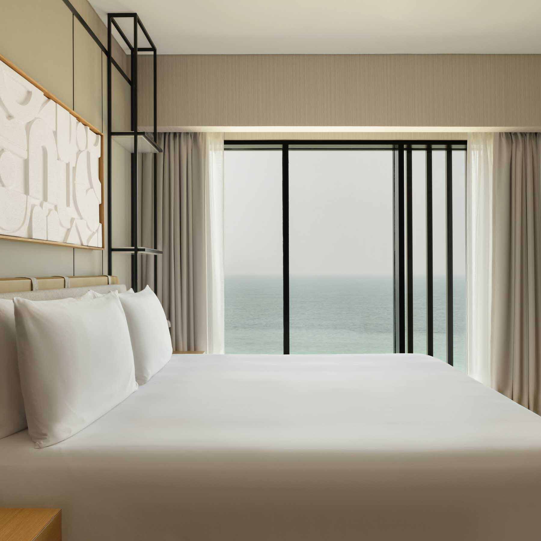 the side view of a king bed in a guestroom with views of the sea