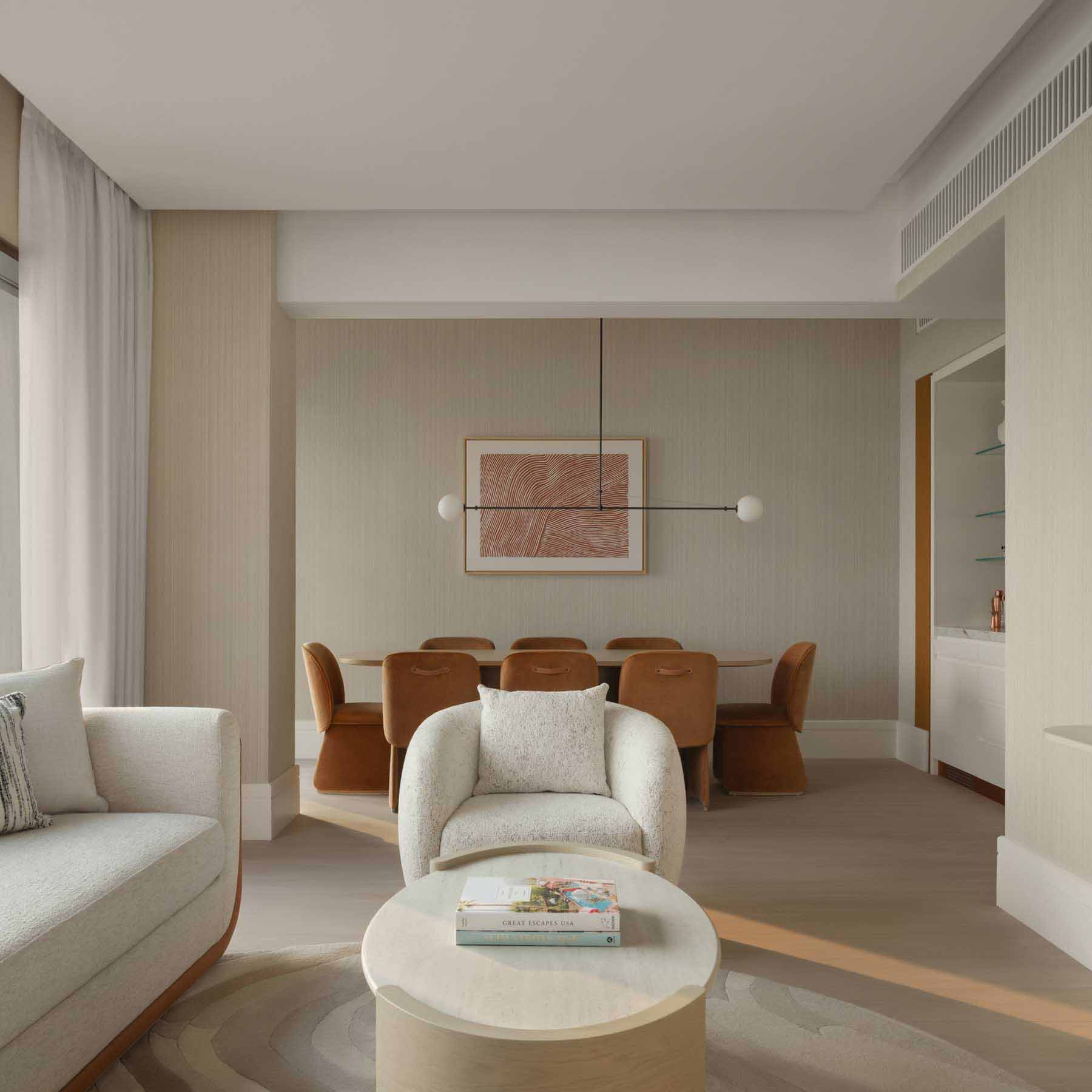a contemporary hotel guestroom with an open planned living space with a white couch and a dining table in the backgroun