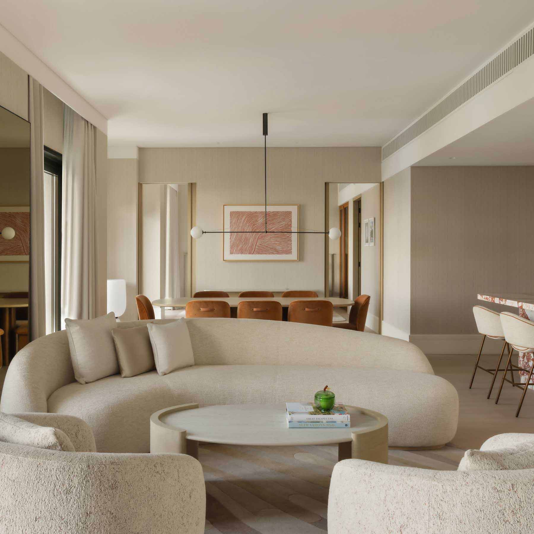 a large living space with a curved white couch and a coffee table and two chairs