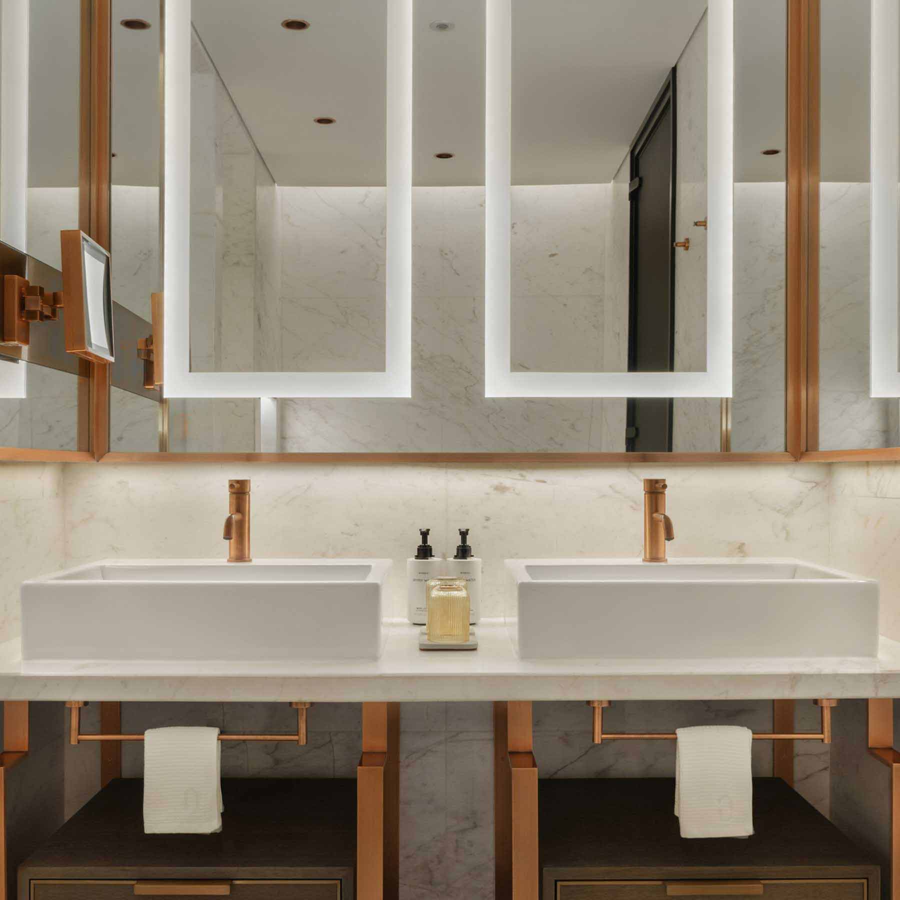 a white marble bathroom with a vanity that has two sinks and a large mirror