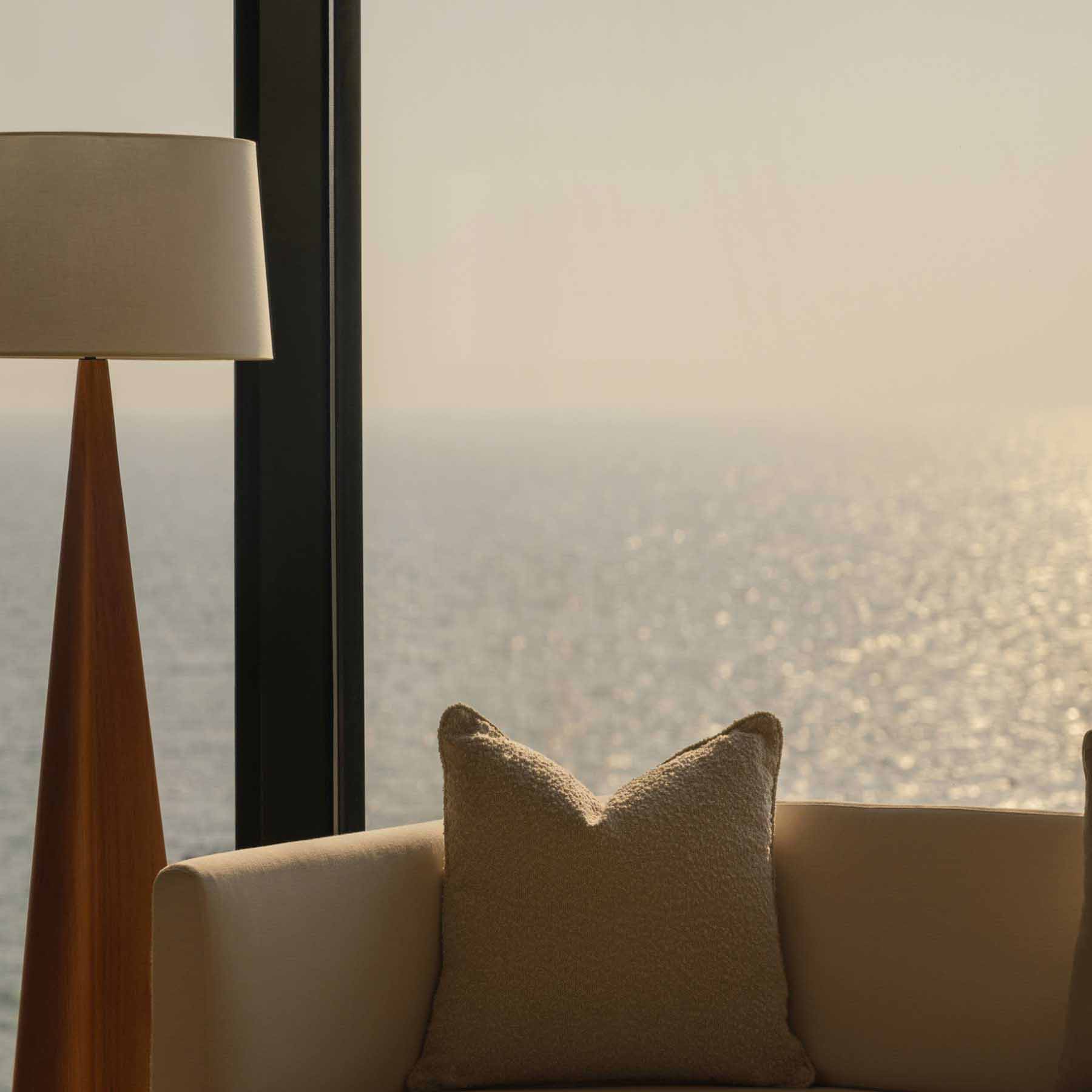 looking over the white couch out the window to sea views at golden hour
