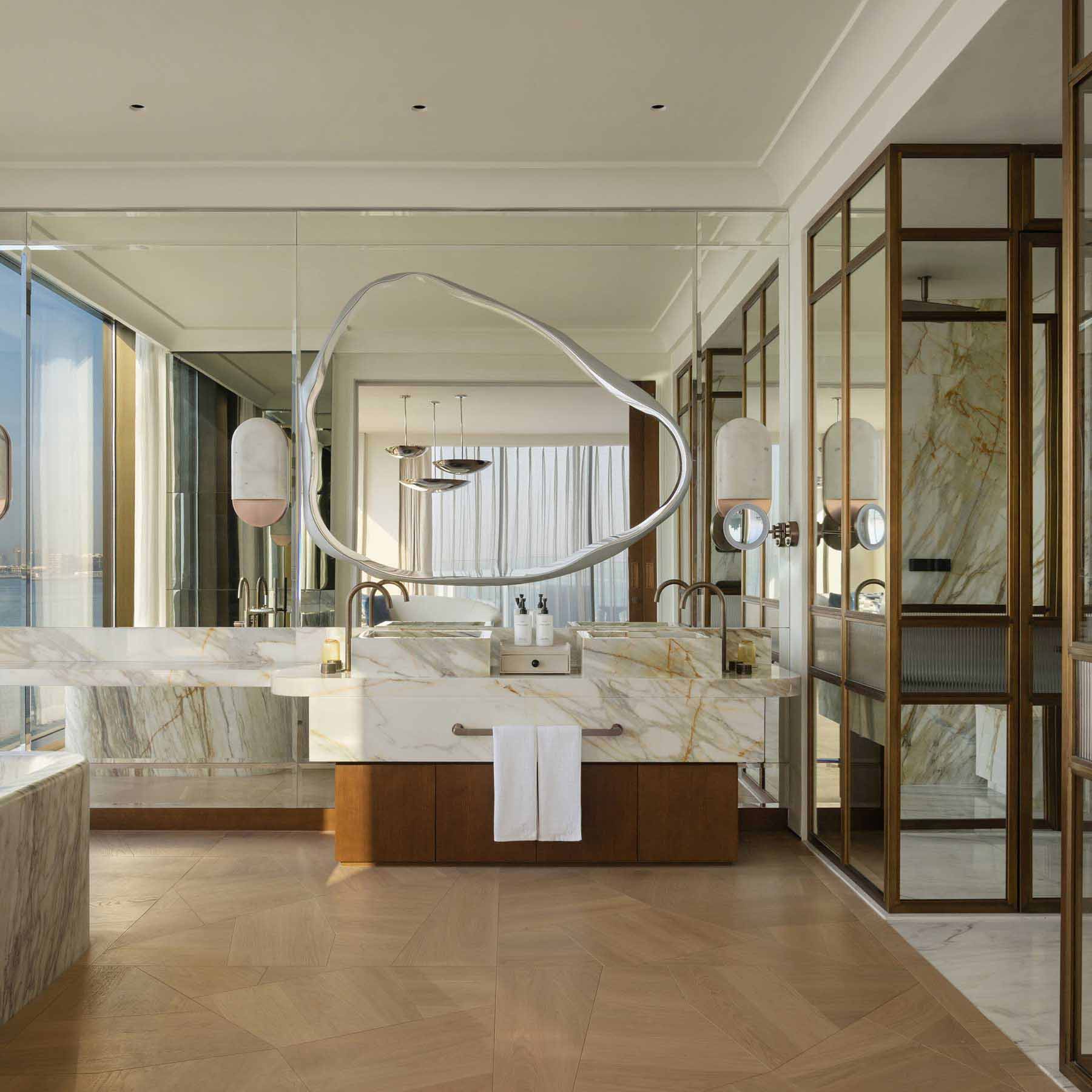 a large batrhoom with marble countertops and artistic mirror