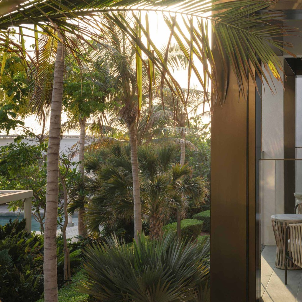 a patio space with woven chairs and views of greenery