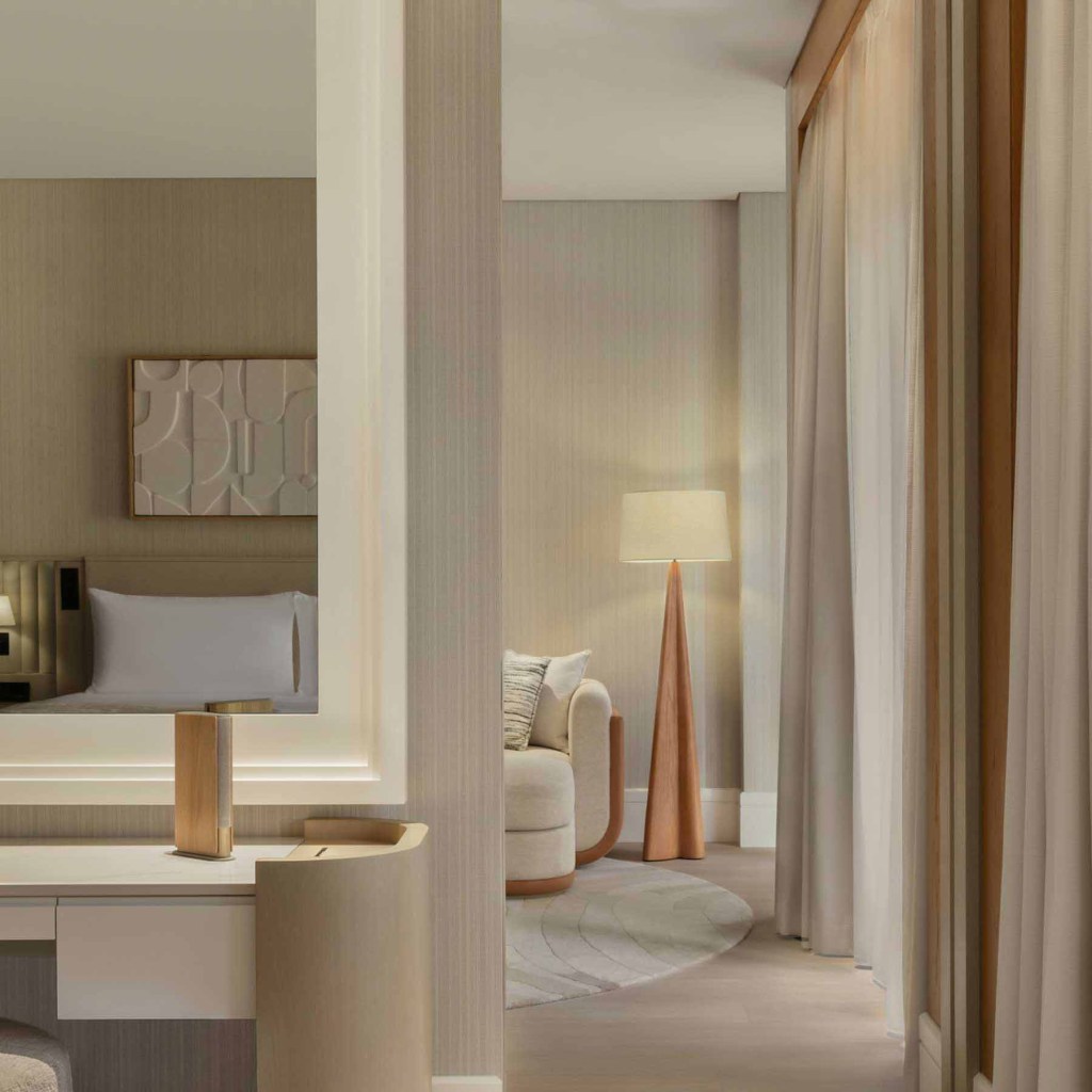 a view into the living room space from the bedroom with the king bed reflecting in the mirror above the desk