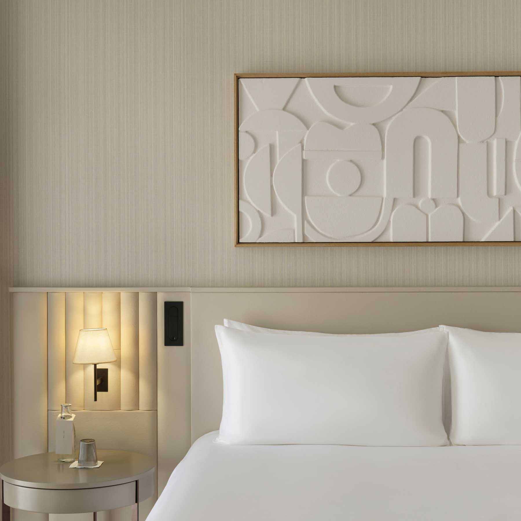 a king bed with a leather headboard, side table with a lit sconce above it