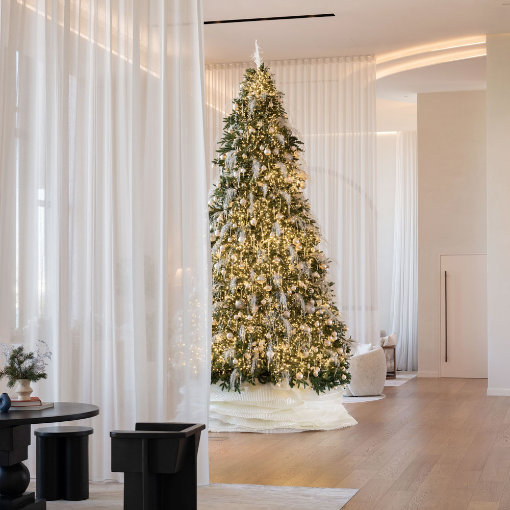 Elegant Christmas tree adorned with golden lights and ornaments in the modern, minimalist lobby of Delano Dubai.