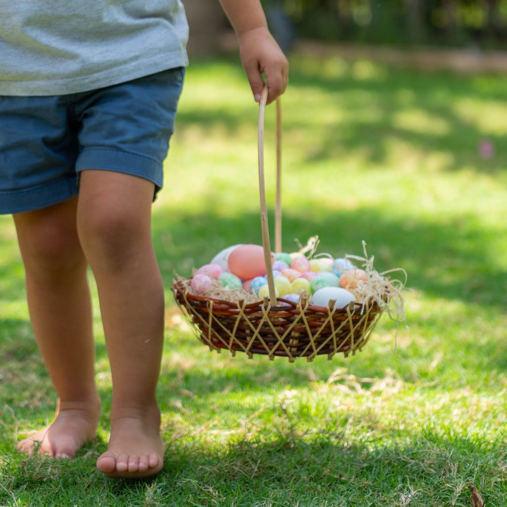 Child holding a basket filled with colourful Easter eggs during an outdoor Easter egg hunt at Delano Dubai.
