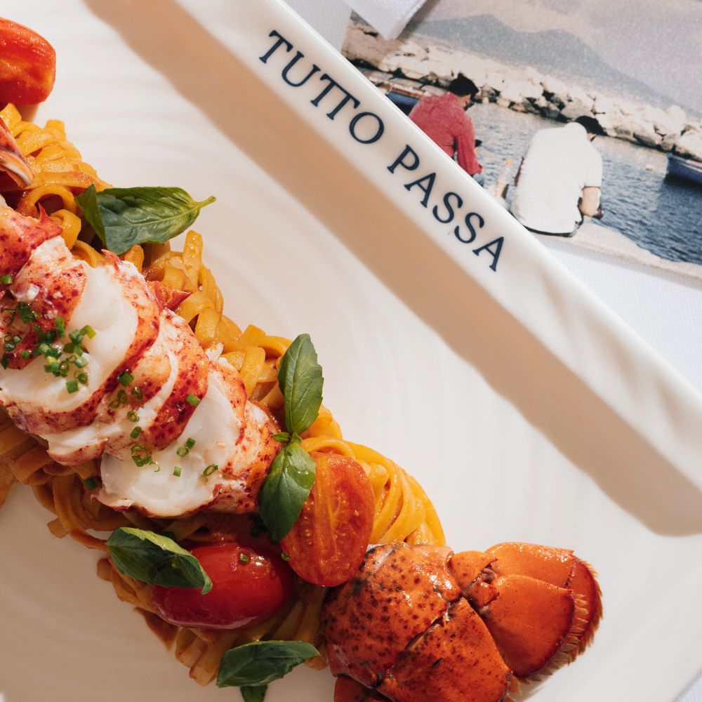 Lobster pasta with cherry tomatoes and fresh basil served on a plate branded Tutto Passa.